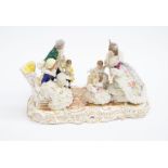 An early 20th century German porcelain figural group of a family meeting grandparents with lace