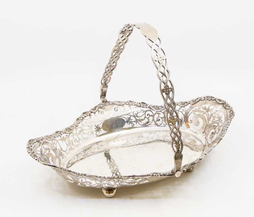 A George V silver basket with ornate pierced work to bordering, and handle, with ball feet to