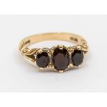 A garnet and 9ct gold ring, comprising three oval garnets within a scrolled mount, size N, total