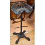 A cast-iron bar/kitchen seat with tractor seat top on an early 20th century cast metal base