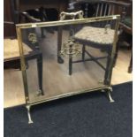 A neo-classical style brass fire screen. With brass frame, lions paw feet, and a stylised fish