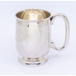 A George V silver one handled mug with baluster form base and plain design to body and gilt