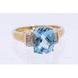 A blue topaz and diamond 9ct gold ring, comprising a checker board cut claw set oval blue topaz