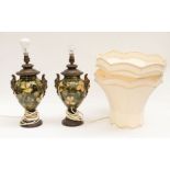 A pair of hand painted Doulton faience lamps with figural mask to handles, metal fittings to bases