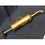 A vintage brass motor pump / syringe with wooden handle, the body with frayed Shell badge,