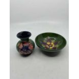 Moorcroft footed bowl decorated with flowers on green ground. Impressed mark Moorcroft to base.