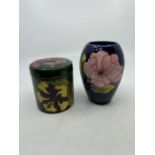 Moorcroft jar and cover of cylindrical form decorated with flowers on green ground. Moorcroft
