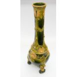 A large glazed art pottery floor vase with three scrolled feet to base, a green background glaze