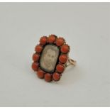 A late 19th century yellow metal and pink coral mourning ring, having central rectangular panel