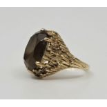 A 9ct. gold and citrine cocktail ring, London 1972, claw set oval mixed cut citrine within highly