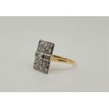 An 18ct. gold, platinum and diamond cluster ring, having rectangular mount set central round