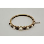 A 9ct. gold, garnet and cultured pearl set hinged bangle, London 1962, the front having claw set