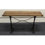 A pitched pine and cast iron patio/garden table, the cleated plank top on scrolled florally cast end