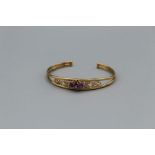 A 9ct gold openwork bangle, set oval and round cut amethysts, the principle stone approximately 5