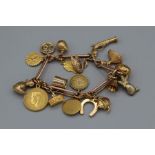 A 9ct gold charm bracelet. Featuring 17 charms, three of which are not gold (coffee bean, two gilded