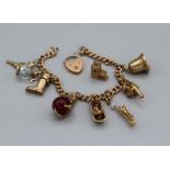 A 9ct gold charm bracelet, featuring a heart shaped padlock clasp and nine charms. The charms