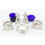 A collection of silver condiment pots consisting of a three footed mustard pot with handle and