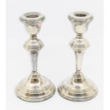 A pair of Elizabeth II weighted candlesticks with circular bases and ribbed designs to sconce,