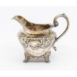 A Victorian silver ogee shaped jug, chased decorative band to upper section, on scroll feet with