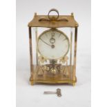 A vintage Kundo mantle clock with brass and glass casing surround, scrolled handle, open movement