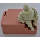 A Michelin bakelite employees money box modelled as a seated Mr. Bibendum, to a pink base, 13cm h