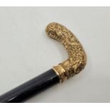 An early 20th century yellow metal handled ebony walking stick, the yellow metal handle chased and