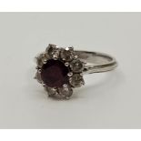 An 18ct. white gold, diamond and ruby ring, set round mixed cut ruby to raised centre, bordered by