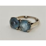 A white metal and two stone aquamarine dress ring, set a pair of mixed round cut aquamarines, fitted