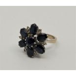 An 18ct. white gold, sapphire and diamond cluster ring, the flower form mount set mixed round cut