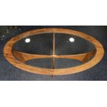 G-Plan - An oval glass topped four legged table, approx. 121cm wide x 43cm high.