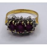 An 18ct gold Ruby and diamond cluster ring. featuring three mixed cut, oval shape rubies and 16