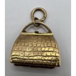 A 9ct gold articulated handbag charm which opens to reveal accoutrements. Approximate weight 8.2