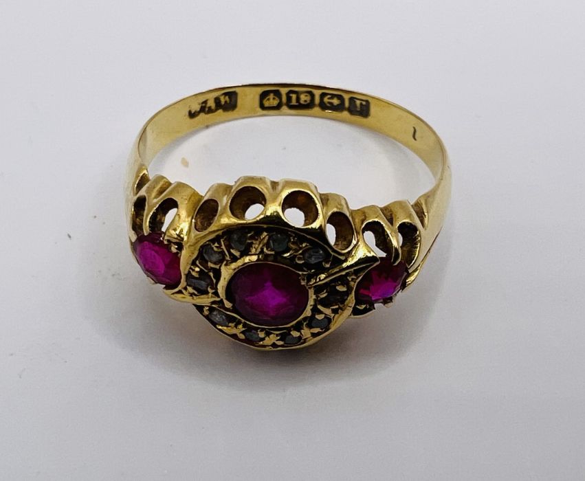 An early 20th century Ruby and diamond set 18ct gold ring. Featuring three rubies, the central stone - Image 3 of 4