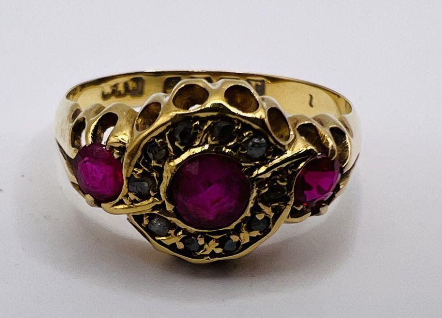 An early 20th century Ruby and diamond set 18ct gold ring. Featuring three rubies, the central stone - Image 2 of 4