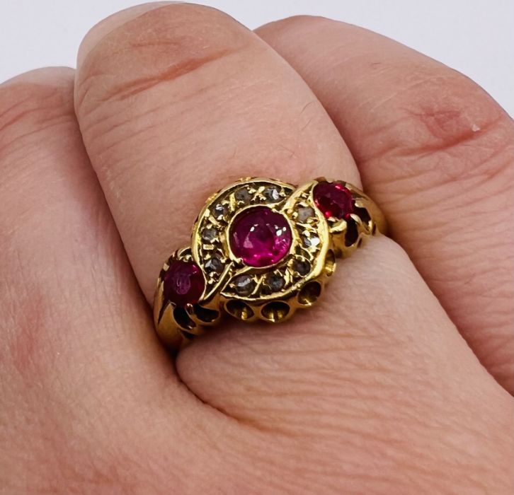 An early 20th century Ruby and diamond set 18ct gold ring. Featuring three rubies, the central stone