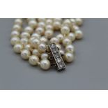 A triple strand of graduated off-round pearls with a diamond set clasp, with an estimated 0.75