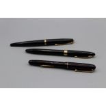 Three fountain pens comprising a Parker pen, black with yellow metal details, a Swan pen in black,