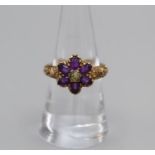 A carved yellow metal amethyst and paste daisy ring. With ornate engraving. There appear to be a