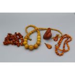 A selection of amber and amber type jewellery, to include a slender graduated egg yolk amber strand.