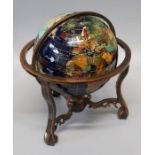 An eight inch terrestrial globe, set with veneers of semi-precious stones, in a bronzed metal cradle