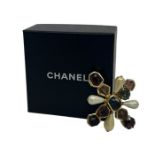 A Chanel brooch in a Byzantine style. Rough cut glass sits in a gold tone cross with two cushion cut
