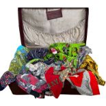 A 1950s suitcase holding a collection of pinnies, 1930s and later, including a 1950s novelty print