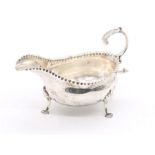 A George III silver oval sauceboat, pinched rim on three shell and hoof feet, S-scroll handle,
