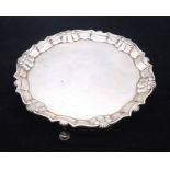 A George II silver salver, raised border with shell and scroll rim, plain centre, on three hoof