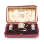 An early 20th century cased silver condiment set to include; mustard pot with blue glass liner,
