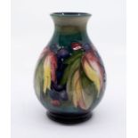 Moorcroft Pottery: A leaves and berry patterned vase, signed and marked to base. Approx. 15cm high x