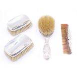 A collection of silver dressing table items to include; a pair of planished silver topped clothes