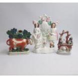 Three Staffordshire figures; a spill holder of a cow standing before bocage, a man and lady standing