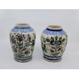 A near pair of Persian Qajar period tin glazed earthenware vases, polychrome painted with flowers,