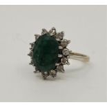 An 18ct. white gold, emerald and diamond ring, set mixed oval cut emerald (13mm x 9mm x 5mm),